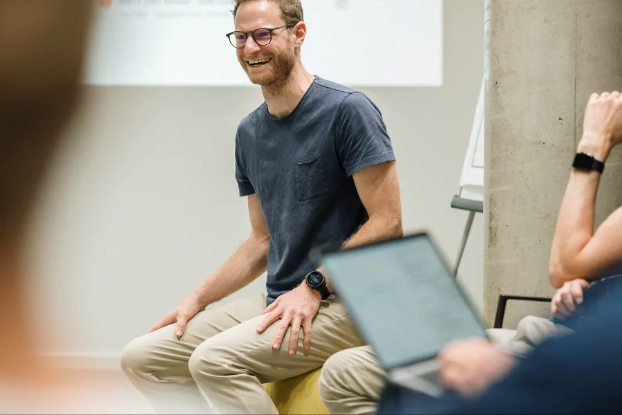 Basti im Stuhlkreis eines Workshops, im Vordergrund der Laptop einer Teilnehmerin